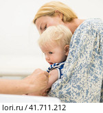 Child beeing vaccinated by pediatrician in presence of his mother. Preventive vaccination against Diphtheria, whooping cough, tetanus, hepatitis, haemophilus influenzae, pneumococcus, poliomyelitis. Стоковое фото, фотограф Matej Kastelic / Фотобанк Лори