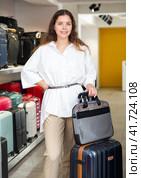Happy woman chose suitcase in haberdashery store. Стоковое фото, фотограф Яков Филимонов / Фотобанк Лори