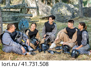 Positive paintball players sitting on battleground and chatting. Стоковое фото, фотограф Яков Филимонов / Фотобанк Лори