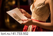 a young woman in an evening dress with a program for a concert in her hands. Стоковое AI-изображение, AI-художник Margarita Davchenko / Фотобанк Лори