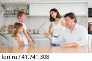 At home in kitchen, outraged mom and dad scold their son and daughter for disobedience. Стоковое фото, фотограф Яков Филимонов / Фотобанк Лори
