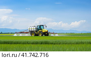 Watering, treating fields with crops with Pesticides and Herbicides on a tractor. Agricultural industry. Стоковое AI-изображение, AI-художник Ирина Ручушкина / Фотобанк Лори