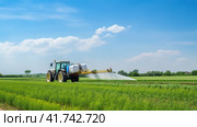 Watering, treating fields with crops with Pesticides and Herbicides on a tractor. Agricultural industry. Стоковое AI-изображение, AI-художник Ирина Ручушкина / Фотобанк Лори
