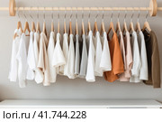 Wooden hangers with clothes on the rail in the store with kid's clothing for sale. Flea market, second hand, discount, exchange, donation. Стоковое AI-изображение, AI-художник Оксана Гильман / Фотобанк Лори
