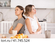 Domestic quarrel - two sisters quarreled in kitchen, sitting back to back. Стоковое фото, фотограф Яков Филимонов / Фотобанк Лори