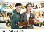Guy male friend strongly recommends his young woman colleague to pay attention to model of boots. Стоковое фото, фотограф Яков Филимонов / Фотобанк Лори