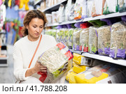 Woman take hay from shelf, inspect label in pet store. Стоковое фото, фотограф Яков Филимонов / Фотобанк Лори