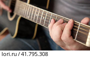Playing the guitar. Strumming black acoustic guitar. Musician plays music. Man fingers holding mediator. Male hand playing guitar neck in dark room. Unrecognizable person rehearsing, fretboard closeup. Стоковое видео, видеограф Марина Демидюк / Фотобанк Лори