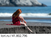 Unrecognizable woman in red dress with raised hem sitting on beach relaxation during beach vacations. Стоковое фото, фотограф А. А. Пирагис / Фотобанк Лори