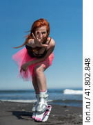 Redhead woman in Kangoo Jumps boots, swimsuit and short skirt posing with an outstretched arm forward into camera during aerobic training session (2022 год). Редакционное фото, фотограф А. А. Пирагис / Фотобанк Лори