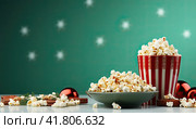 A plate and a glass of fresh popcorn on the table next to a green background. Generated by AI. Стоковое AI-изображение, AI-художник Ярославский Максим / Фотобанк Лори