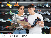 Guy with girlfriend, view specialized shoes in store, near showcase with summer trecking cross-shoes. Стоковое фото, фотограф Яков Филимонов / Фотобанк Лори