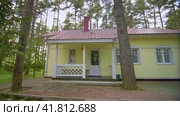 Cozy yellow guest house with white porch surrounded by pine trees. Стоковое видео, видеограф Даниил Хабаров / Фотобанк Лори