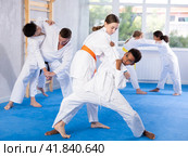 Teen girl honing grappling techniques during kumite with boy at karate training. Стоковое фото, фотограф Яков Филимонов / Фотобанк Лори