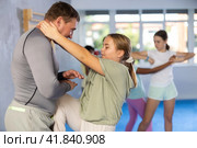 Tween girl performing knee strike in midsection to instructor in self-defense sparring. Стоковое фото, фотограф Яков Филимонов / Фотобанк Лори