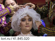 Женщины одевают фату и готовят невесту к свадьбе по традициям Донской казачьей свадьбы на выставке-форуме "Россия" на ВДНХ в городе Москве, Россия (2023 год). Редакционное фото, фотограф Николай Винокуров / Фотобанк Лори