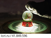 New Year composition. Traditional beautiful Snow globe with Santa Claus inside of it. Human leg in military boot wants to destroy symbol of holiday. Concept of unfulfilled hopes, instability in world. Стоковое фото, фотограф YuryKara / Фотобанк Лори