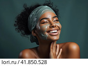 A young and very beautiful African girl with a green cosmetology mask on her face looks away with a smile and blissfully smiles. Стоковое AI-изображение, AI-художник Ярославский Максим / Фотобанк Лори