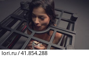 Slim brunette caught in metal BDSM cage eating a chocolate. Стоковое видео, видеограф Гурьянов Андрей / Фотобанк Лори