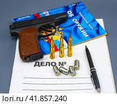 Пистолет, патроны, авторучка и закон "Об оружии" на папке "Дело №" (2023 год). Редакционное фото, фотограф Анна Аникова / Фотобанк Лори