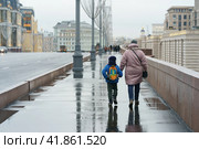 Семья идет по мокрой улице Москвы в дождливый день (2019 год). Стоковое фото, фотограф YuryKara / Фотобанк Лори