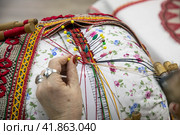 Крупным планом мастерица ткет михайловское кружево на стенде Рязанской области на выставке-форуме "Россия" в городе Москве, Россия (2023 год). Редакционное фото, фотограф Николай Винокуров / Фотобанк Лори