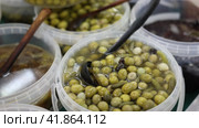 Pickled olives, onion and cucumbers in plastic container on market. Popular vegetarian appetizer. Стоковое видео, видеограф Яков Филимонов / Фотобанк Лори