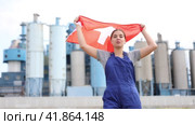 Happy young woman worker holding big flag of Switzerland against background of factory. Стоковое видео, видеограф Яков Филимонов / Фотобанк Лори