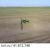Tractor with hinged system of spraying pesticides. Fertilizing with a tractor, in the form of an aerosol, on the field of winter wheat. Стоковое фото, фотограф Леонид Еремейчук / Фотобанк Лори