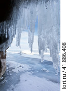 Winter Baikal Lake. A look at the endless fields of ice from the ice grotto in the coastal cliffs on a cold sunny day. Traveling on a frozen lake. Cool background. Стоковое фото, фотограф Виктория Катьянова / Фотобанк Лори