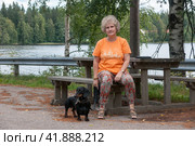 Elderly woman with black and tan dachshund sits on park bench by lake in summer. Стоковое фото, фотограф Алексей Антипов / Фотобанк Лори