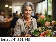 Portrait of a senior woman in a retirement home happily enjoying a healthy lunch. Presentation of a healthy lifestyle of well-being and contentment even at an age. Стоковое AI-изображение, AI-художник Ирина Михайличенко / Фотобанк Лори