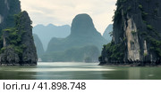 Beautiful view of the sea bay with karst limestone islets and cliffs on a cloudy day. Стоковое AI-изображение, AI-художник Евгений Харитонов / Фотобанк Лори
