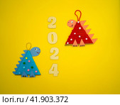 Christmas tree toys a dragon made by a child out of cardboard and threads lies on a yellow background. The symbol of 2024. Educational and craft activity. Стоковое фото, фотограф Ирина Старикова / Фотобанк Лори