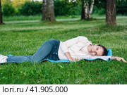 Portrait of dreamful woman lying on green grass in park. Стоковое фото, фотограф Константин Григорьев / Фотобанк Лори