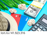 Платежные карты МИР и VISA с соломенной шляпой пачкой долларов и калькулятором на голубом фоне. Концепция отпускных расходов. (2024 год). Редакционное фото, фотограф Ярославский Максим / Фотобанк Лори