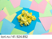 A bunch of yellow crumpled yellow pieces of paper on a blue background among colorful pieces of paper. The concept of finding an idea. Стоковое фото, фотограф Ярославский Максим / Фотобанк Лори