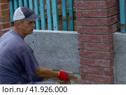 The builder lays tiles on the building's enclosing wall from the outside. Стоковое фото, фотограф Светлана Зотова / Фотобанк Лори