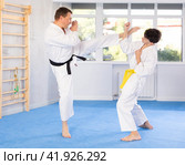Underage boy and middle-aged man performing karate techniques in pair. Стоковое фото, фотограф Яков Филимонов / Фотобанк Лори
