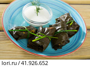 Grape rolls in leaves at plate with sour cream, dish of Bulgarian cuisine. Стоковое фото, фотограф Яков Филимонов / Фотобанк Лори