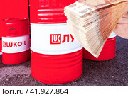 Branded Lukoil oil company barrels and russian rubles in the hand (2019 год). Редакционное фото, фотограф FotograFF / Фотобанк Лори