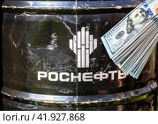 Barrel of Rosneft motor oil and russian roubles in the hand (2022 год). Редакционное фото, фотограф FotograFF / Фотобанк Лори