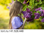 Cute little girl in dress laughing in spring park near lilac. child smells lilac. Стоковое фото, фотограф Ирина Михайличенко / Фотобанк Лори