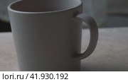 A grey clay cup stands on the kitchen table.the passage is from right to left. Cinematic light. Стоковое видео, видеограф Ярославский Максим / Фотобанк Лори