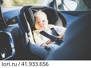 Cute little baby boy strapped into infant car seat in passenger compartment during car drive. Стоковое фото, фотограф Matej Kastelic / Фотобанк Лори