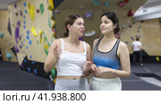 Women are standing in gym and discussing possible options for overcoming difficult climbing route. Стоковое видео, видеограф Яков Филимонов / Фотобанк Лори