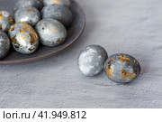 Stylish grey Easter eggs made of marble and concrete with a golden potala on a grey background. Coloring eggs with natural dye karkade tea. Environmental friendliness. Naturalness. The concept of a happy Easter. (2023 год). Стоковое фото, фотограф Photojuli / Фотобанк Лори