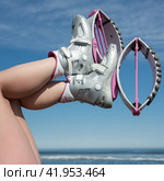 View of female legs up in air shod in sports Kangoo Jumps boots during outdoor fitness workout on background of sky and beach on sea coast (2022 год). Редакционное фото, фотограф А. А. Пирагис / Фотобанк Лори