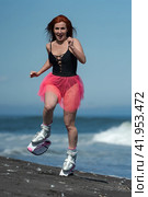 Woman trainer in sports Kangoo Jumps boots, black swimsuit and short skirt running and jumping on black sandy beach during fitness exercise outdoors (2022 год). Редакционное фото, фотограф А. А. Пирагис / Фотобанк Лори