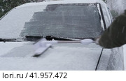 Person brushing fresh snow from car windows after snow storm blizzard. Morning routine difficulties of car owners in cold winter weather. Car window cleaning. Winter season. White snow. Vehicle care. Стоковое видео, видеограф Марина Демидюк / Фотобанк Лори